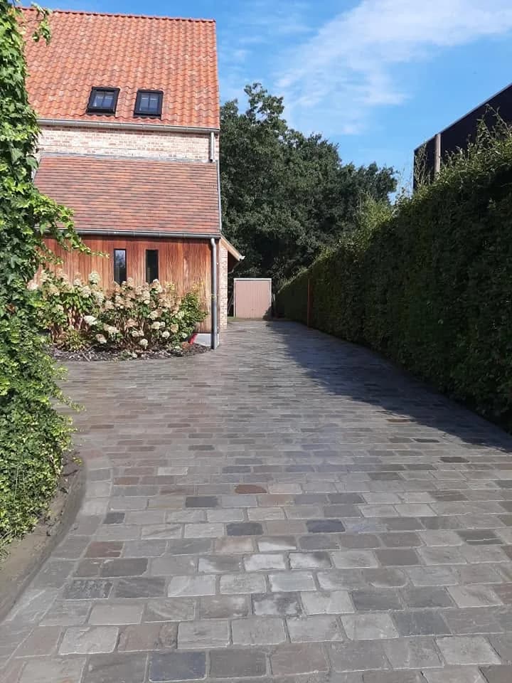 Afgewerkte oprit in kasseien langs de woning, richting de tuinberging