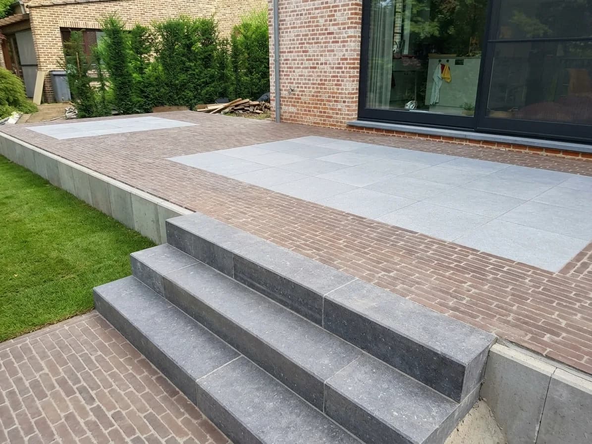 Afgewerkt terras in klinkers met natuursteen platines en een trap in blauwe hardsteen