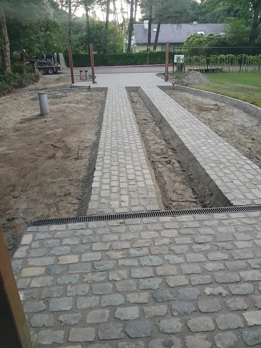 Oprit in aanleg met twee rijstroken in kasseien en een lijngoot