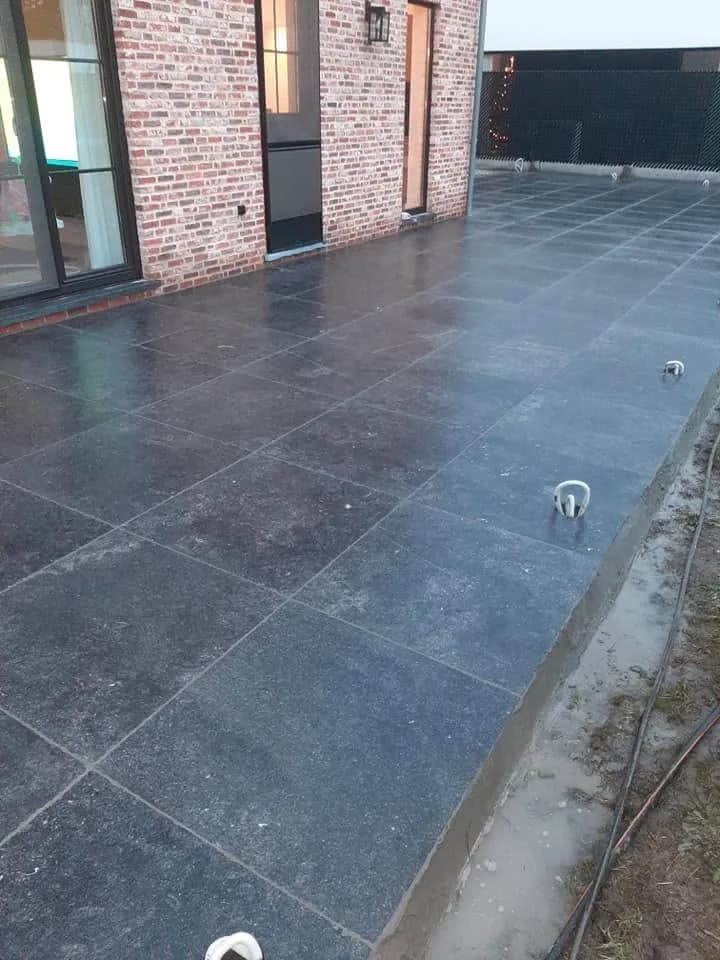 Terras in grote natuurstenen tegels, aansluitend op de gevel
