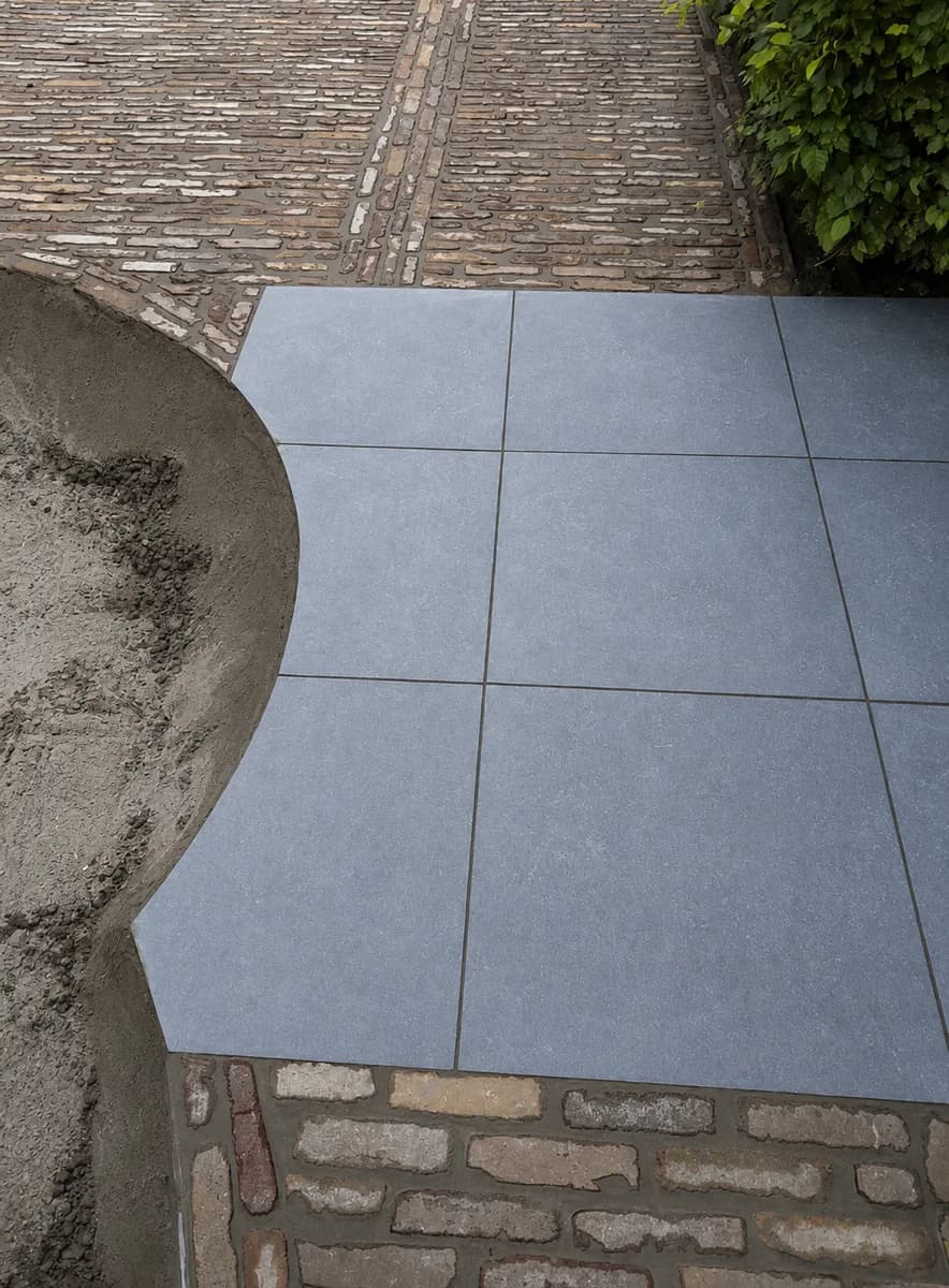 Detail van grote terrastegels naast een strook oude kasseien
